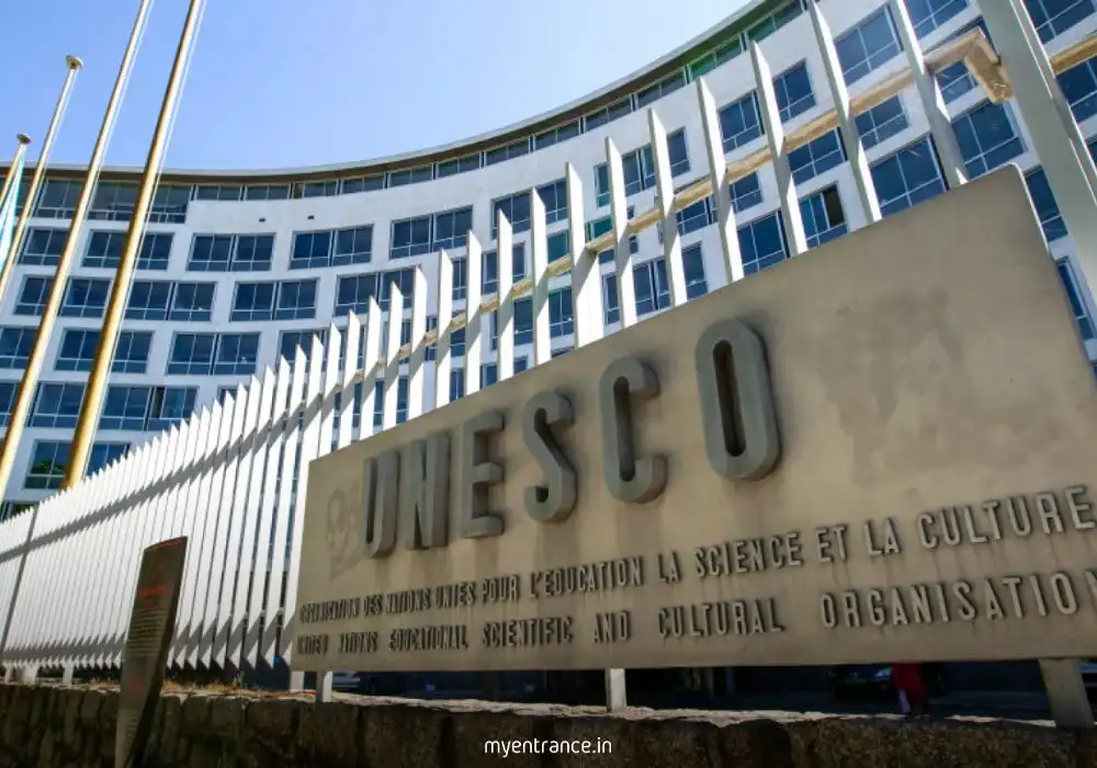 UNESCO headquarters building in Paris with a globe sculpture and international flags.