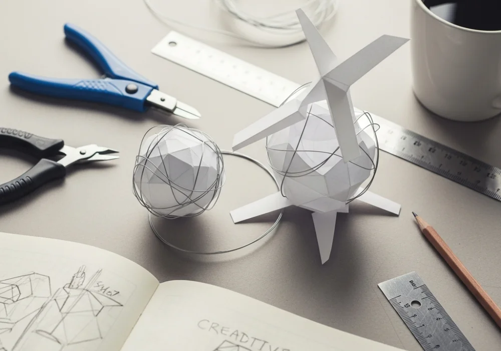 A professional designer workspace with a 3D model, craft tools, and sketches for NIFT Situational Test preparation.