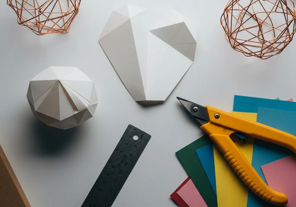 Expert NIFT Situation Test preparation with 3D paper models and craft tools on a clean workspace.